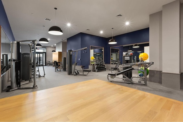 gym with a towering ceiling and wood-type flooring