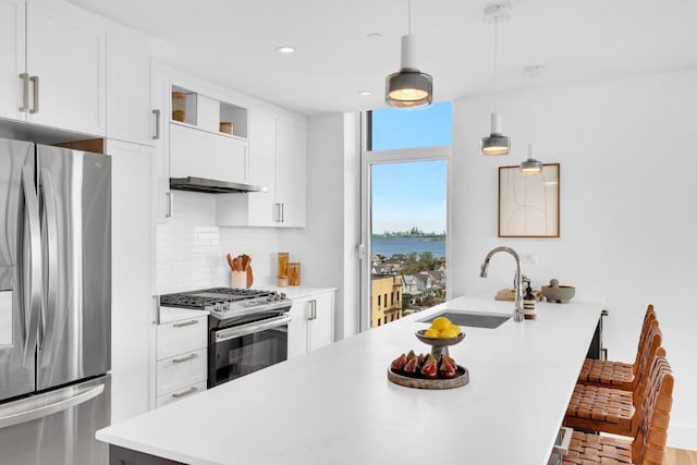 kitchen with appliances with stainless steel finishes, sink, hanging light fixtures, and white cabinets