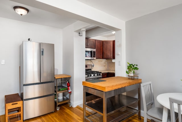 kitchen with light wood-type flooring, visible vents, tasteful backsplash, appliances with stainless steel finishes, and baseboards