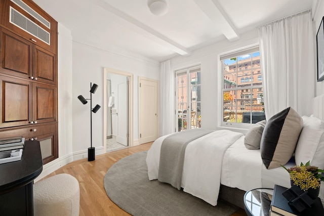 bedroom featuring light wood-type flooring, beamed ceiling, visible vents, ensuite bath, and baseboards