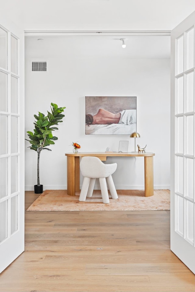 unfurnished office featuring visible vents, light wood-style flooring, and baseboards