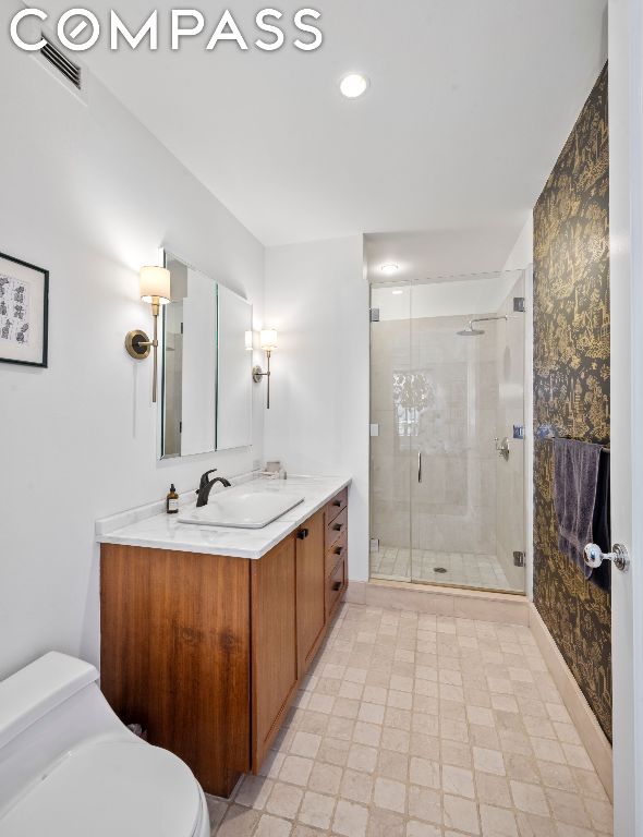 bathroom with a shower with shower door, toilet, and vanity