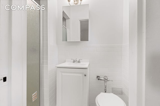 full bathroom with toilet, a stall shower, vanity, and tile walls