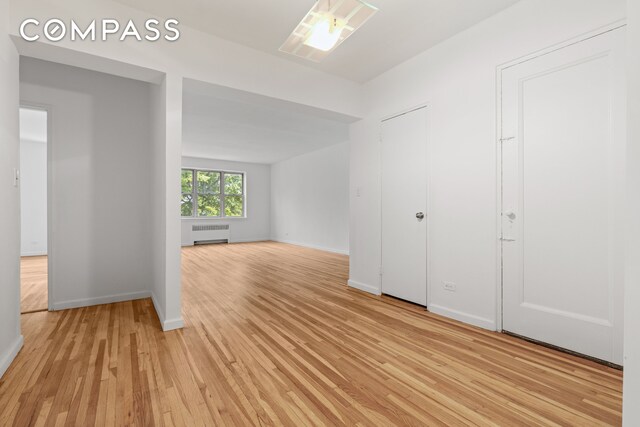 empty room with radiator, a wealth of natural light, and light hardwood / wood-style flooring