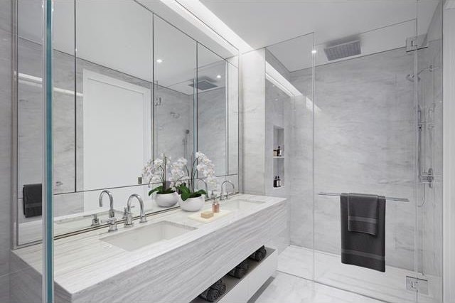 full bath with a sink, tile walls, a stall shower, and double vanity