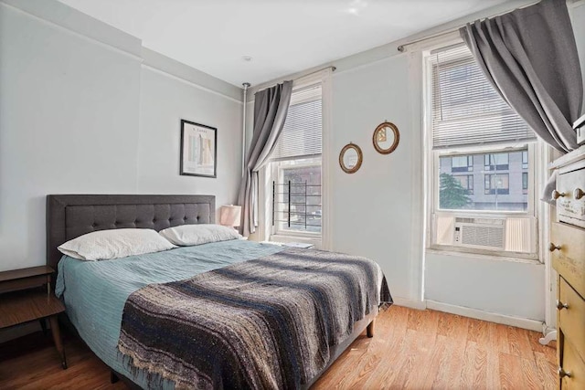 bedroom featuring cooling unit, wood-type flooring, and multiple windows