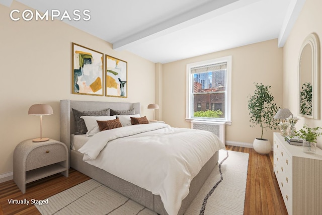 bedroom featuring hardwood / wood-style floors, beam ceiling, and radiator heating unit