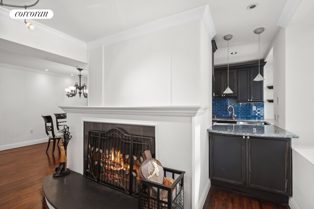 living room featuring dark wood-type flooring, a fireplace, sink, and crown molding