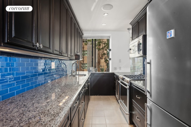 kitchen with sink, light tile patterned floors, stone counters, appliances with stainless steel finishes, and backsplash