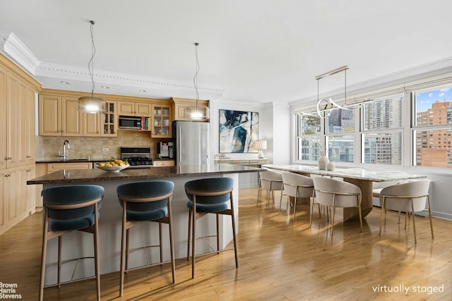 kitchen with a kitchen bar, backsplash, appliances with stainless steel finishes, crown molding, and a healthy amount of sunlight