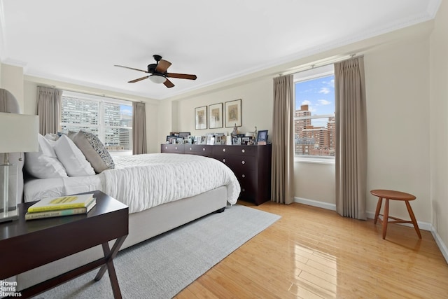 bedroom featuring baseboards, a ceiling fan, crown molding, and light wood finished floors