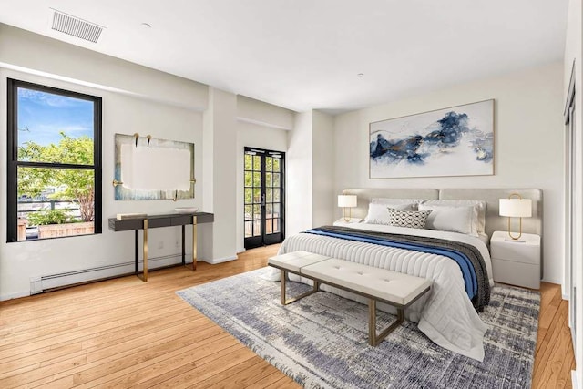 bedroom featuring visible vents, a baseboard heating unit, and wood-type flooring