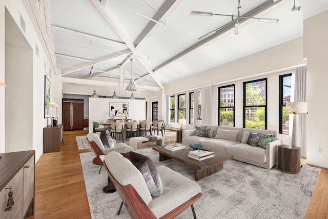 living room with beam ceiling, high vaulted ceiling, and light wood-type flooring