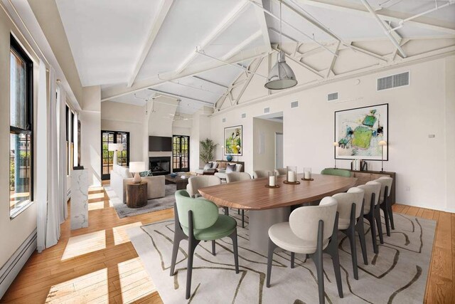 dining room with beamed ceiling, high vaulted ceiling, light hardwood / wood-style floors, and a baseboard heating unit