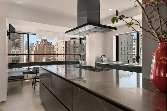 kitchen featuring a city view, island exhaust hood, stone countertops, concrete floors, and stainless steel gas cooktop