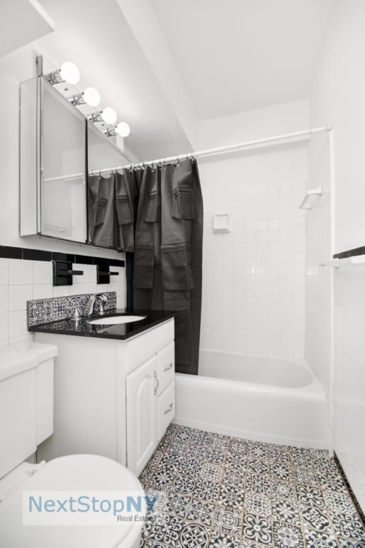 full bathroom featuring shower / bathtub combination with curtain, tile patterned flooring, tile walls, vanity, and toilet