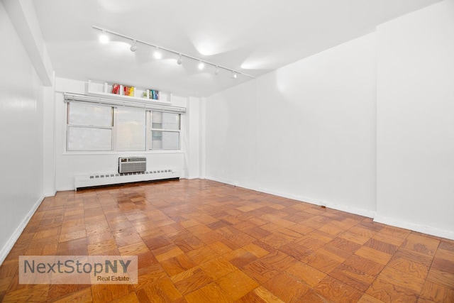 spare room with baseboards, a wall unit AC, and baseboard heating