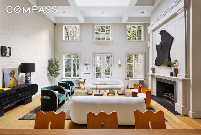 living room with coffered ceiling, radiator, hardwood / wood-style flooring, a towering ceiling, and beam ceiling