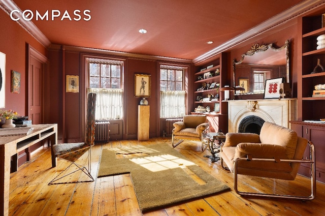 sitting room with hardwood / wood-style flooring, radiator heating unit, and ornamental molding