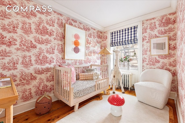 bedroom with wood-type flooring, ornamental molding, and radiator heating unit