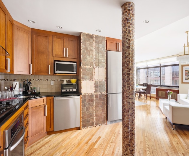 kitchen featuring sink, light wood-type flooring, appliances with stainless steel finishes, and decorative backsplash