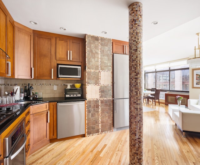 kitchen with stainless steel appliances, dark countertops, brown cabinets, and backsplash