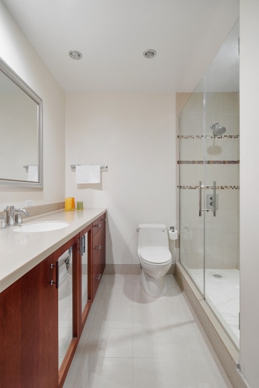 bathroom with toilet, tile patterned floors, vanity, and a shower with shower door