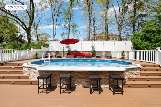 view of swimming pool featuring outdoor dry bar, an outdoor hangout area, a wooden deck, and a fenced backyard