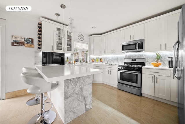 kitchen featuring hanging light fixtures, a breakfast bar area, stainless steel appliances, and white cabinets