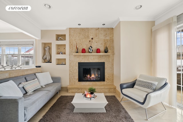 living room with built in features, ornamental molding, and a tile fireplace