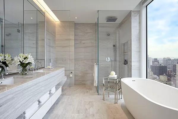 full bathroom with tile walls, double vanity, a tile shower, a sink, and a freestanding tub