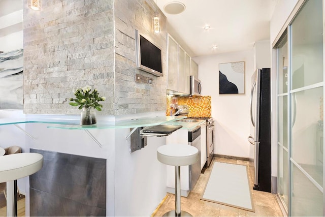 kitchen featuring tasteful backsplash, kitchen peninsula, and stainless steel appliances