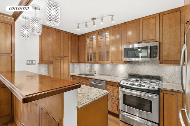 kitchen featuring backsplash, pendant lighting, sink, appliances with stainless steel finishes, and light stone counters