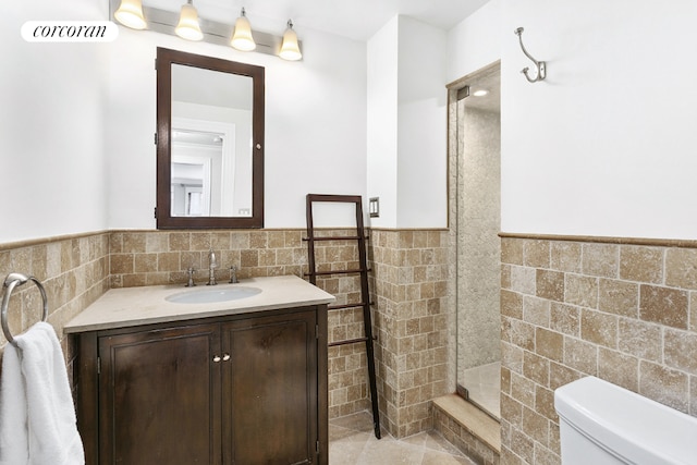 bathroom featuring tile patterned floors, tile walls, toilet, and vanity