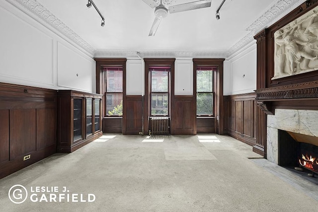 unfurnished living room featuring plenty of natural light, light carpet, crown molding, and a fireplace