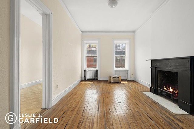 unfurnished living room with hardwood / wood-style flooring, radiator heating unit, and crown molding