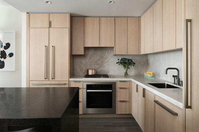 kitchen featuring appliances with stainless steel finishes, light brown cabinetry, decorative backsplash, and sink