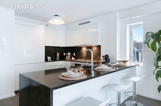 kitchen featuring dark countertops, white cabinets, modern cabinets, and backsplash