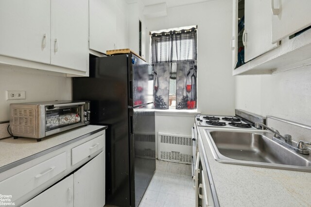 800 Grand Concourse Unit Gms, New York City, NY 10451 - kitchen with radiator, a sink, white cabinetry, and light countertops