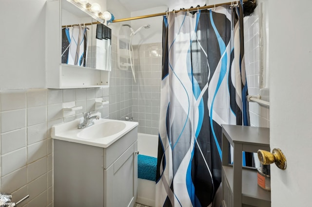 full bath featuring tile walls, shower / tub combo with curtain, vanity, and tasteful backsplash