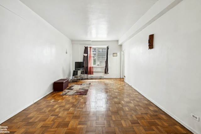 unfurnished living room featuring baseboards and radiator heating unit