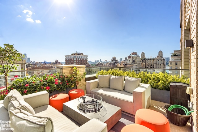 view of patio with a view of city, an outdoor living space with a fire pit, and a balcony