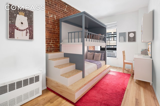 bedroom featuring hardwood / wood-style floors, radiator heating unit, and baseboards