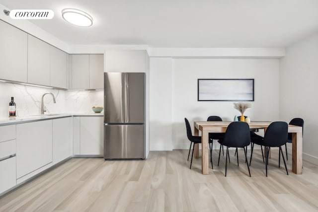 kitchen with visible vents, freestanding refrigerator, a sink, light countertops, and backsplash