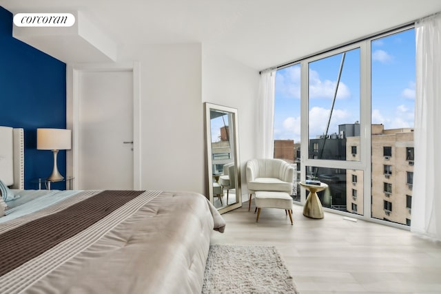 bedroom with visible vents, floor to ceiling windows, and wood finished floors