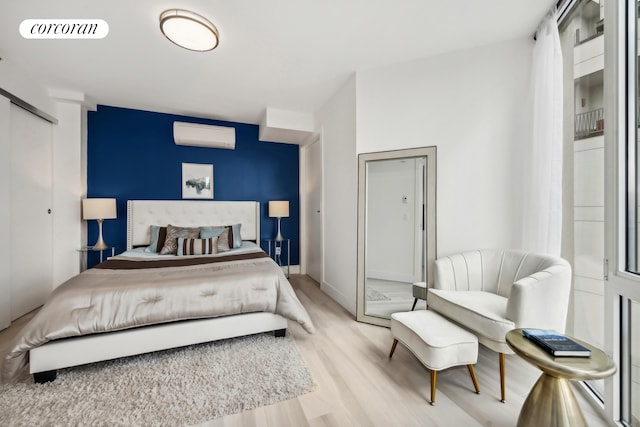 bedroom featuring visible vents, light wood-style flooring, and a wall mounted AC