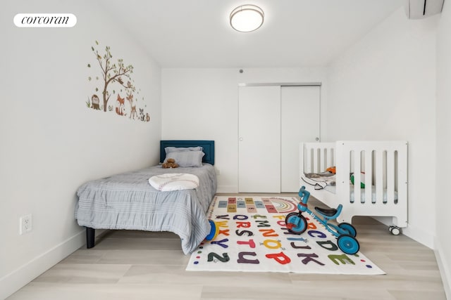 bedroom with visible vents, baseboards, a closet, and a wall mounted AC