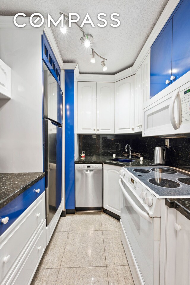 kitchen with dark stone counters, white cabinets, tasteful backsplash, and white appliances