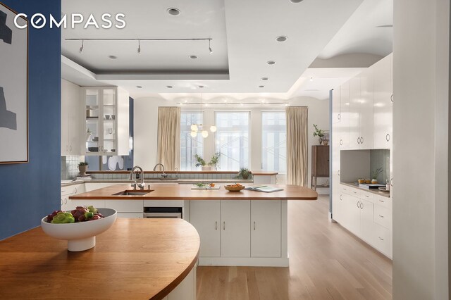 114 Liberty St Unit 7, New York City, NY 10006 - kitchen with a tray ceiling, white cabinetry, decorative backsplash, light wood finished floors, and recessed lighting
