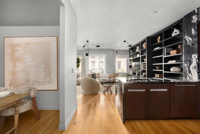 kitchen featuring built in features, dark brown cabinets, light hardwood / wood-style flooring, and sink